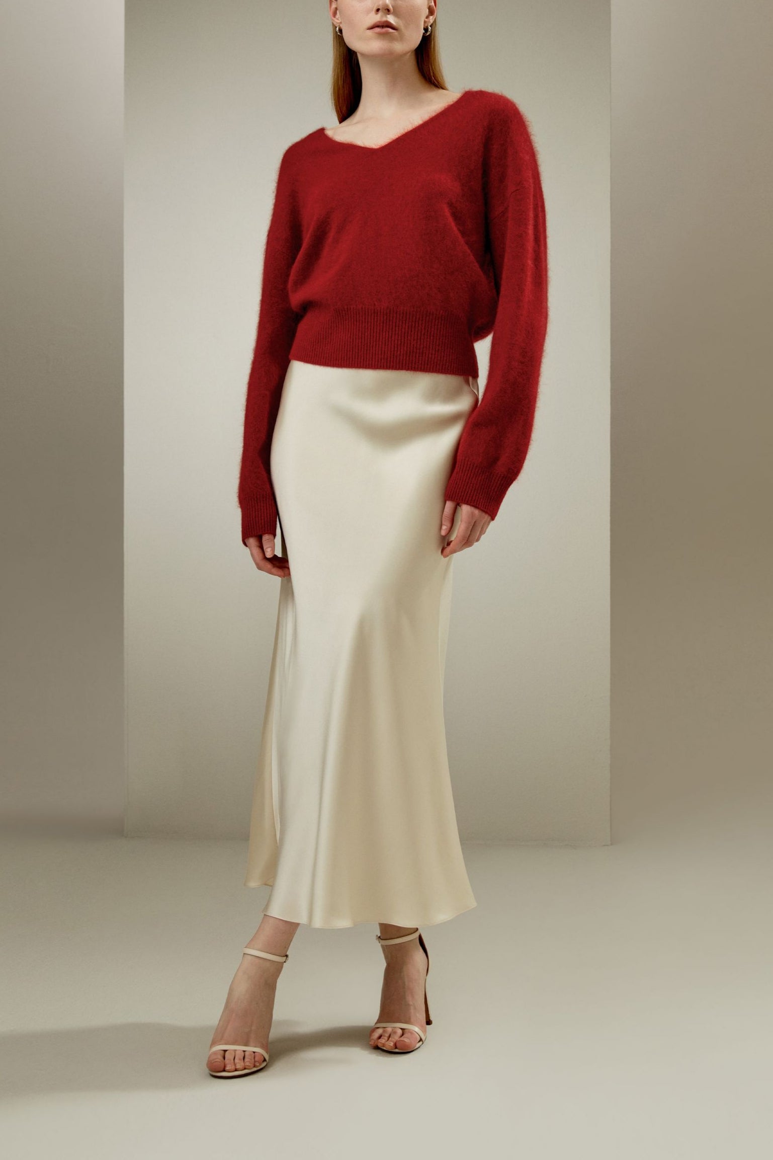 flare paça ipek maksi etek kombin görünümü, kadın kırmızı kazak ve krem ipek etek uyumu